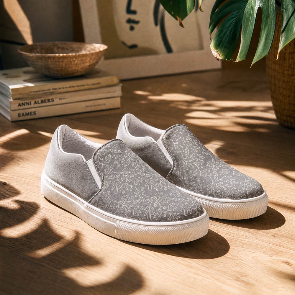 His Good Stuff's Autumn Catalog HGS26S4 Slipper Shoes, lifestyle view, breathable lining, soft insole, elastic side accents, padded collar and tongue, in an everyday environment. Ultimate Gray with cloud dancer white oak leaf floral pattern over the toes.