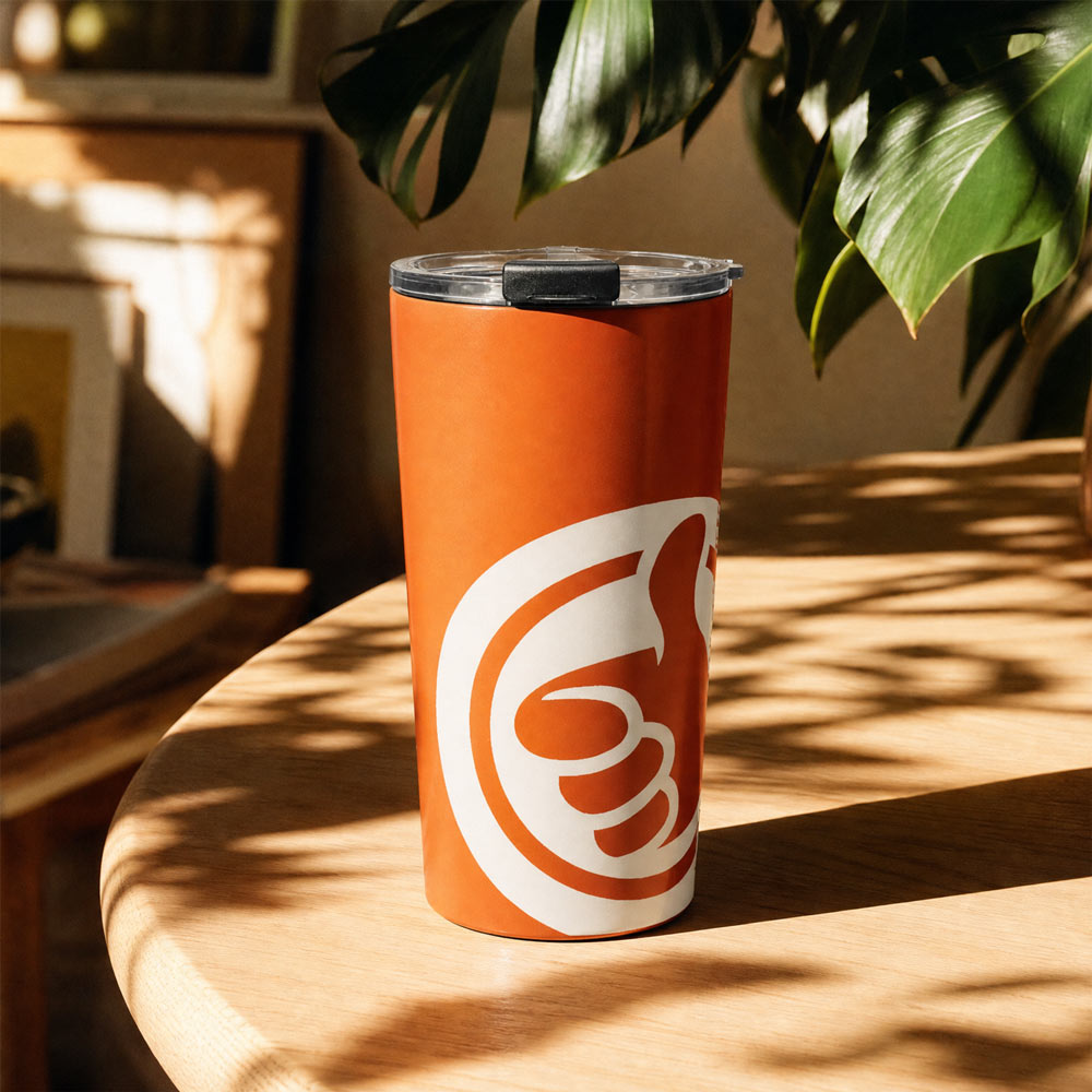 His Good Stuff's Autumn Catalog HGS26S4 Travel Tumbler, front lifestyle view, 20 oz, glossy stainless steel, vacuum-sealed insulation, in a everyday environment. Graphics display a cloud dancer white HGS thumbs-up icon.