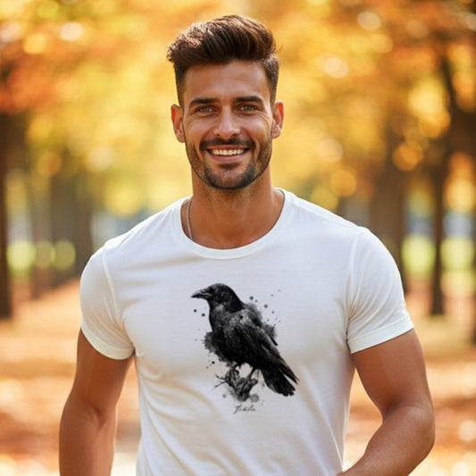 A man wearing an HGS Corvus Familiar White Tee with black ink Raven Illustration in an outdoor setting