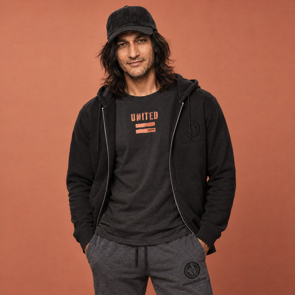 His Good Stuff's Autumn Catalog HGS26S4 Corduroy Cap, front, 100% cotton corduroy with an adjustable golden buckle in the back, on a model against a flat Brandied Melon background. Graphic displays in black thread, 3-D embroidered HGS26S4