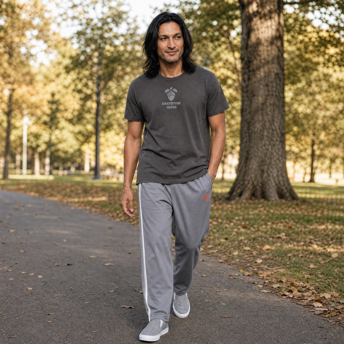 His Good Stuff's Autumn Catalog HGS26S4 Cotton Pants, front, wide-leg, heavyweight cotton-spandex blend, ultimate grey with 2 cloud dancer white stripes, on a model walking outside in a city park in the Fall. Graphic displays in the top right a brandied-melon-colored HGS Fall thumbs-up icon.