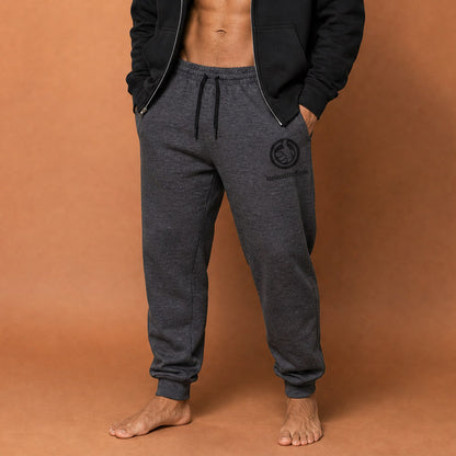 His Good Stuff's Autumn Catalog HGS26S4 Fleece Joggers, front closeup, tapered fit, preshrunk fleece, heather black, on a model against a flat Brandied Melon background. Graphic displays in the top right a black thread embroidery of a HGS Fall thumbs-up icon over HisGoodStuff.com