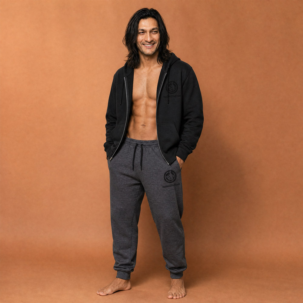 His Good Stuff's Autumn Catalog HGS26S4 Fleece Joggers, front, tapered fit, preshrunk fleece, heather black, on a model against a flat Brandied Melon background. Graphic displays in the top right a black thread embroidery of a HGS Fall thumbs-up icon over HisGoodStuff.com