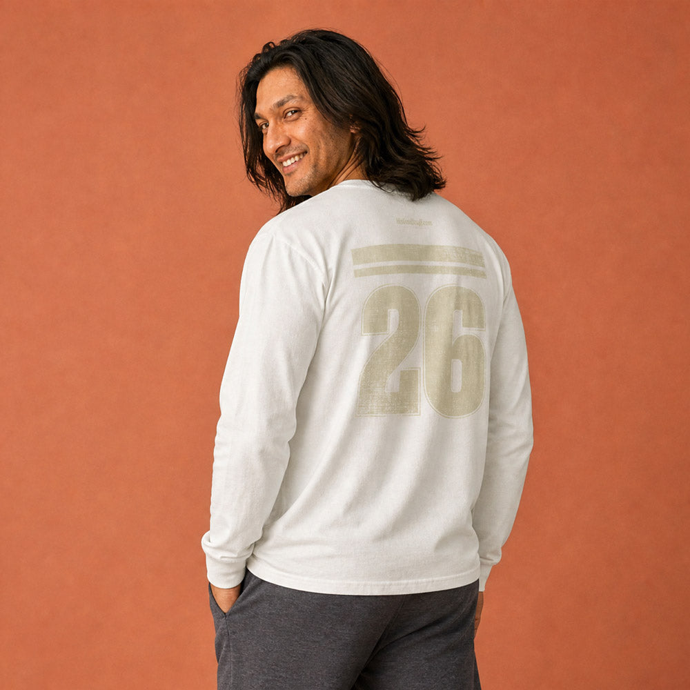 is Good Stuff's Autumn Catalog HGS26S4 Gratitude Jersey, back, heavyweight, 100% ring-spun cotton, white, long-sleeve on model against a flat Brandied Melon background. Graphic displays two bars over a distressed number 26.