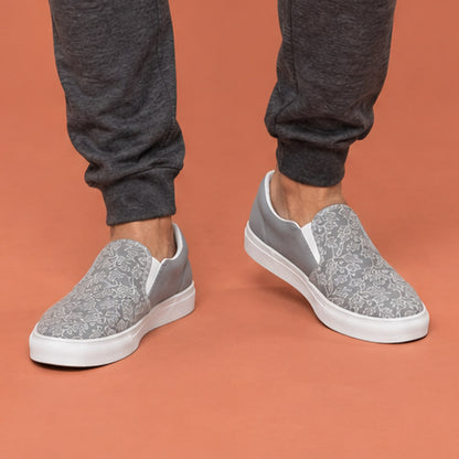 His Good Stuff's Autumn Catalog HGS26S4 Slipper Shoes, front closeup, breathable lining, soft insole, elastic side accents, padded collar and tongue, on a model against a flat Brandied Melon background. Ultimate Gray with cloud dancer white oak leaf floral pattern over the toes. 