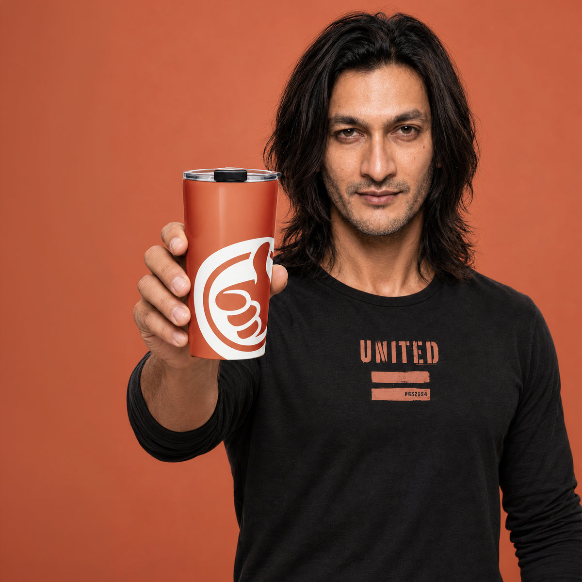 His Good Stuff's Autumn Catalog HGS26S4 Travel Tumbler, front view, 20 oz, glossy stainless steel, vacuum-sealed insulation, with a model against a flat Brandied Melon background. Graphics display a cloud dancer white HGS thumbs-up icon.