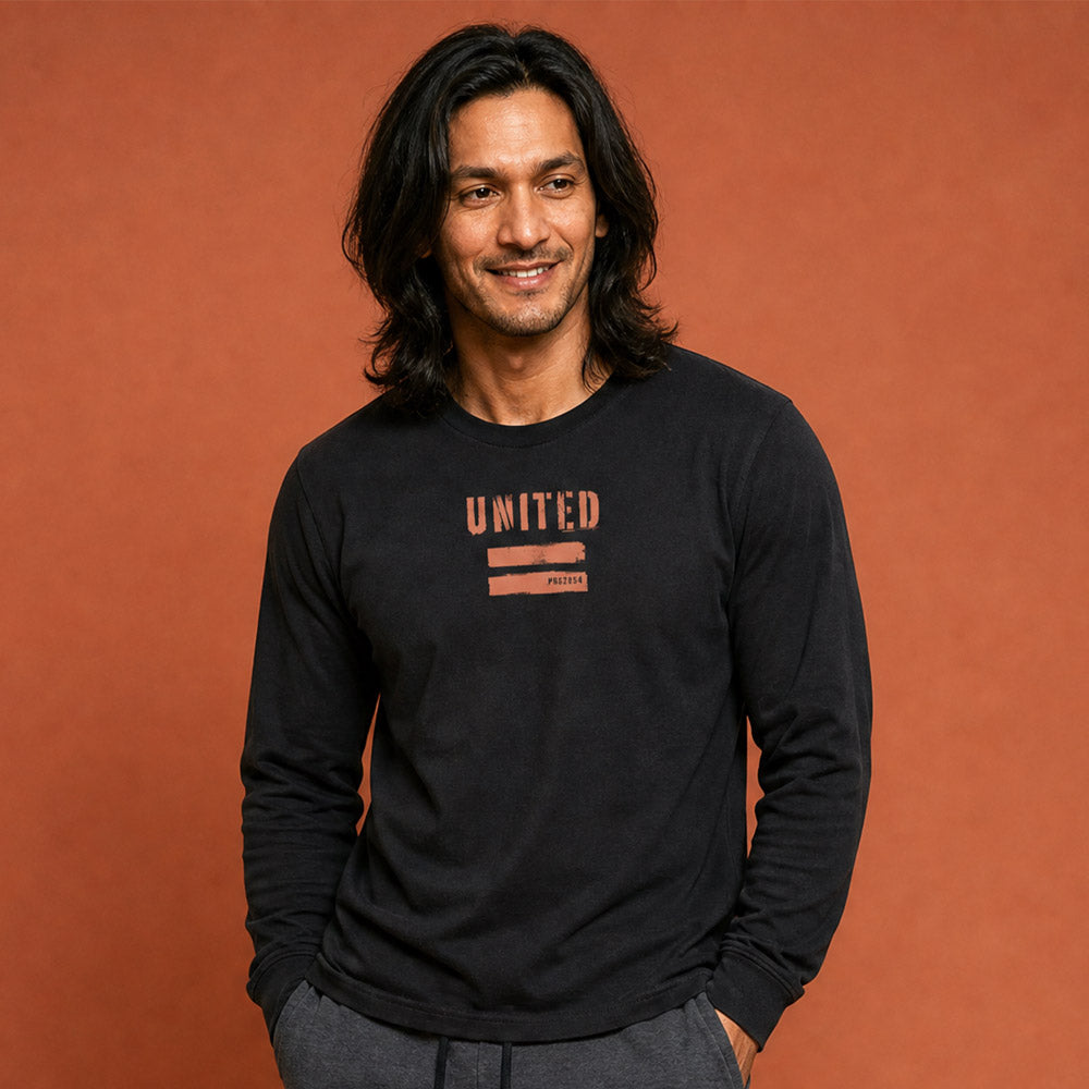 His Good Stuff's Autumn Catalog HGS26S4 United Equality, front, close up, heavyweight, 100% ring-spun cotton, black, long-sleeve, detail of fabric against a flat Brandied Melon background. Graphic displays two bars beneath the distressed letters "EQUALITY".