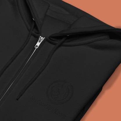 His Good Stuff's Autumn Catalog HGS26S4 Zip Hoodie, front fabric detail, relaxed fit, black fleece, matching round drawcord with metal eyelets and tipped end, on a flat Brandied Melon background. Graphic displays in the top right a black embroidered HGS Fall thumbs-up icon with HisGoodStuff.com underneath